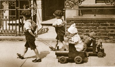 Kinder spielen auf der Straße: Jungen ziehen Karren von English Photographer